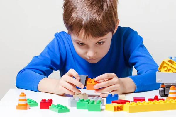 テーブルにカラフルなプラスチックおもちゃのブロックと遊ぶ子供. — ストック写真