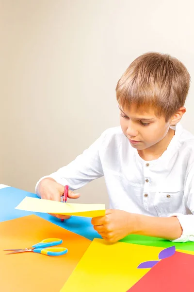 Детская резка цветной бумаги с ножницами за столом — стоковое фото