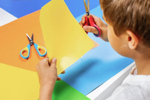 Corte infantil de papel de color con tijeras en la mesa — Foto de Stock