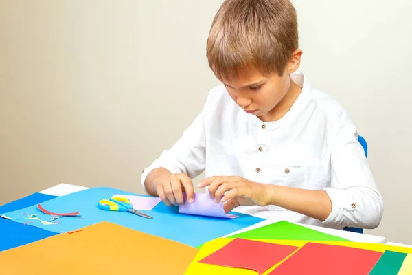 Criança fazendo cartão de saudação com papel colorido na mesa — Fotografia de Stock