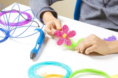 Çocuk el beyaz masa üzerinde renkli filamentler 3D kalem ile oluşturma.