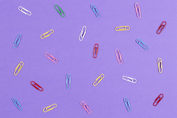 Colourful paper clips on violet background