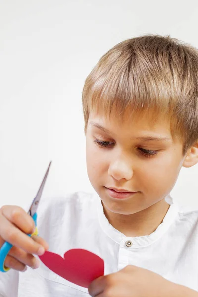 Bambino taglio rosso cuore di carta con le forbici — Foto Stock