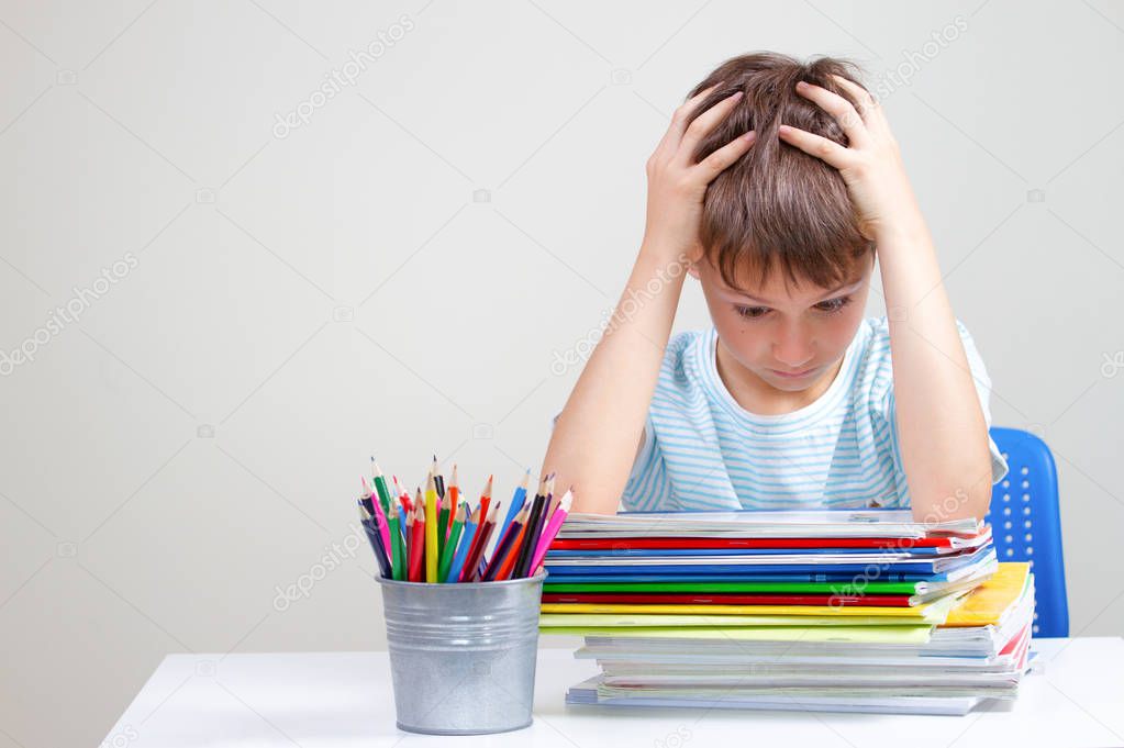 The boy sitting and looking in to books and notebooks. Education, school, learning difficulties concept