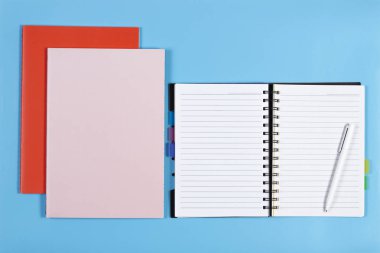 Açık defter ile beyaz kalem ve mavi arka plan üzerinde renkli Notebook