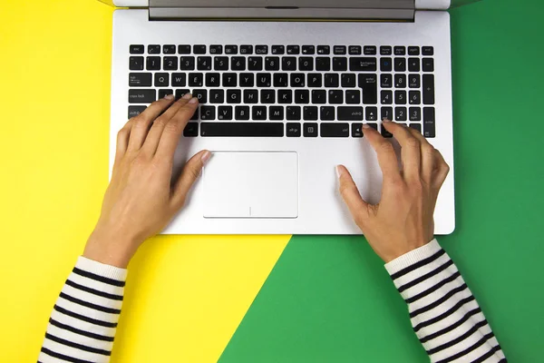 Woman hands typing on laptop computer on colorful background