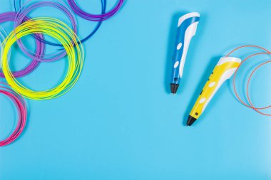 mavi arka plan üzerinde renkli plastik filaman ile 3D kalemler