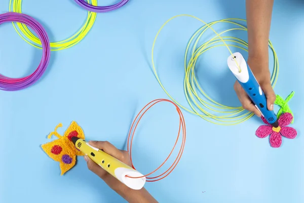 Çocuklar el ile 3d kalem ve mavi masada renkli filamentler — Stok fotoğraf