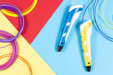 renkli arka plan üzerinde plastik filaman ile 3D kalemler.