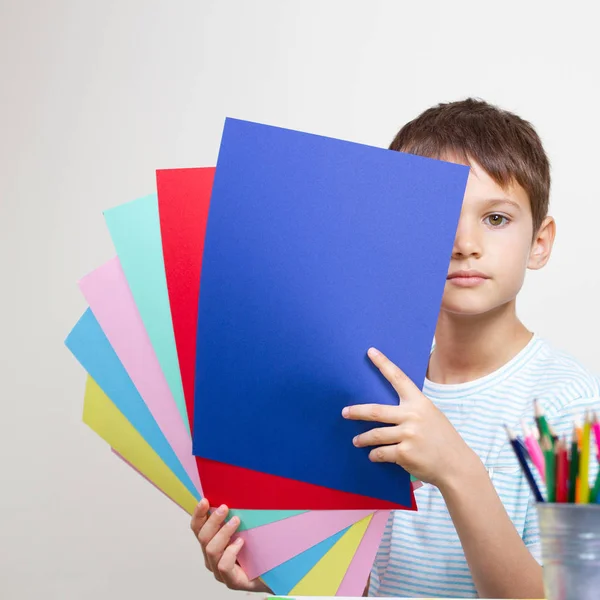 テーブルに座って色紙を持つ少年 — ストック写真