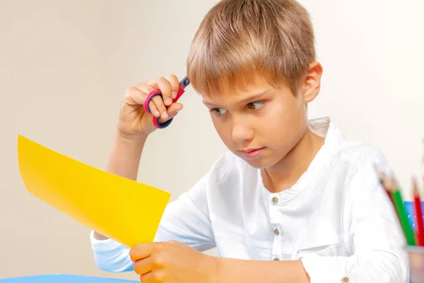 Criança cortando papel colorido com tesoura na mesa — Fotografia de Stock