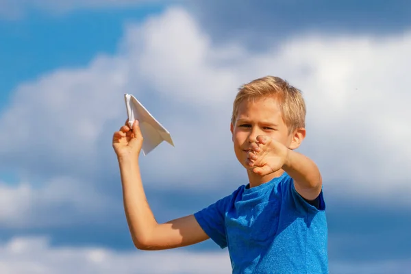 Junge wirft Papierflieger gegen blauen Himmel — Stockfoto