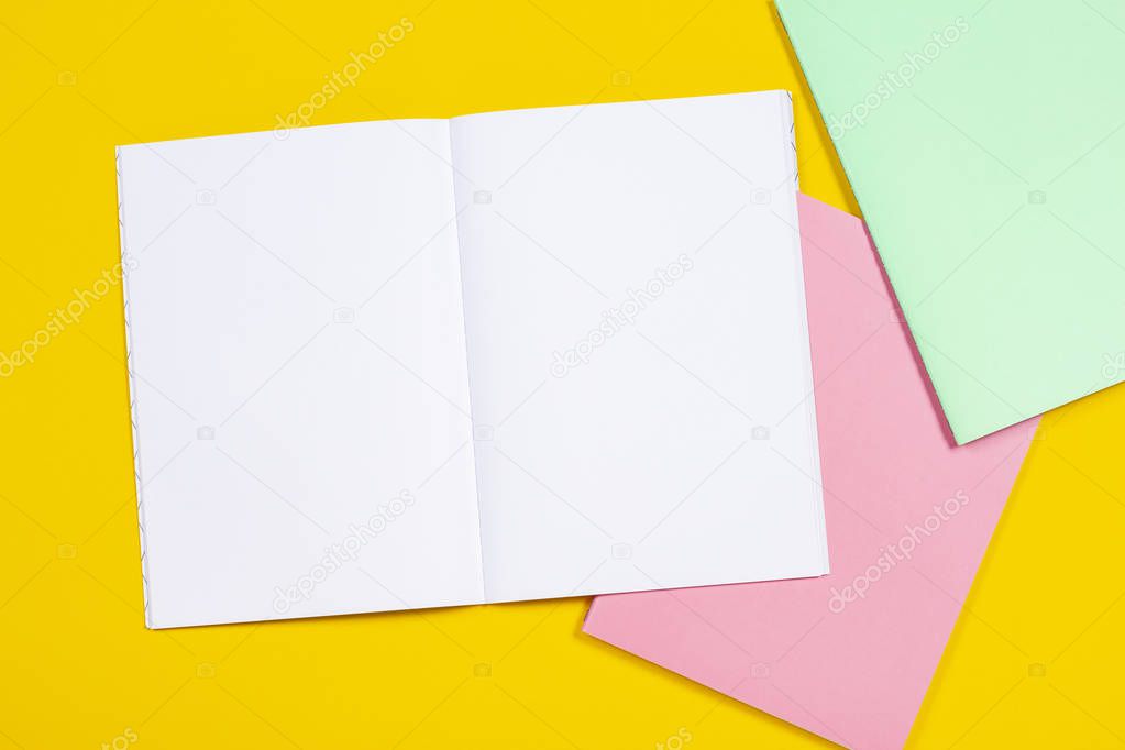 Open notebook and colorful notebooks on yellow background