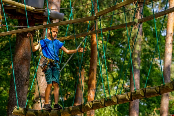 Niño disfrutando de la actividad en un parque de aventura escalada en un día de verano — Foto de Stock