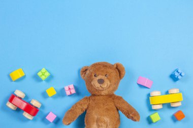 Bebek Çocuk oyuncakları arka plan. Oyuncak ayı, ahşap araba, mavi arka plan üzerinde renkli tuğlalar
