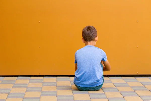 야외에서 다채로운 벽 근처에 앉아 슬픈 혼자 소년 — 스톡 사진