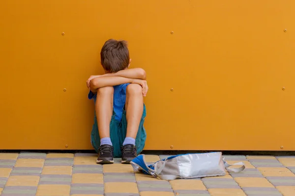 Triste solo chico sentado cerca colorido pared al aire libre — Foto de Stock