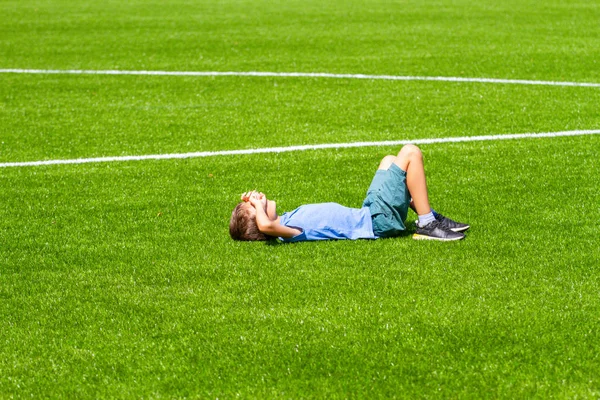 Jongen liggend op het voetbalveld — Stockfoto