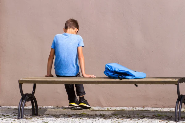 Niño triste y cansado sentado solo en el banco al aire libre . — Foto de Stock