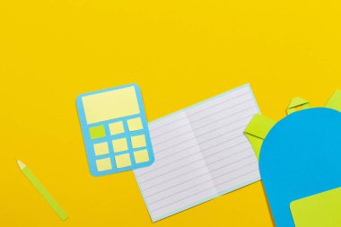 Okul eğitim Kağıt arka plan. Okul çantası sırt çantası, Notebook ve hesap makinesi kağıt üzerinde sarı arka plan kesmek