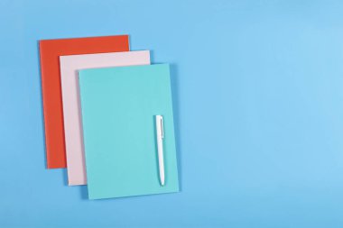 Renkli Notebook ve mavi arka plan, üstten görünüm üzerinde beyaz kalem