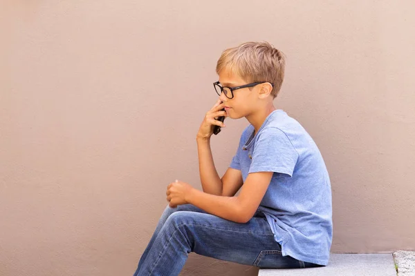 Kid talar i mobiltelefon mot färgglada byggnaden vägg utomhus — Stockfoto