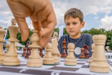Children playing chess at chessboard outdoors. Boy thinking hard on chess combinations clipart