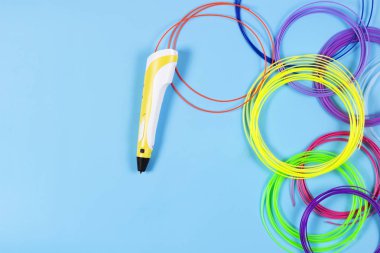 mavi arka plan üzerinde renkli plastik filaman ile 3D kalem