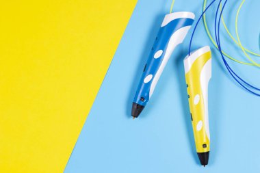 mavi ve sarı arka plan üzerinde renkli plastik filaman ile 3D kalemler.