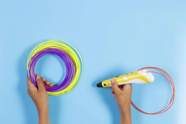 Niño dibuja con pluma 3d. Niña sosteniendo la pluma 3d con filamento de plástico — Foto de Stock