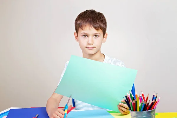 Chlapče, řezání barevný papír s nůžkami v tabulce — Stock fotografie