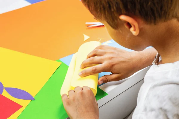 Criança fazendo cartão de saudação com papel colorido na mesa — Fotografia de Stock