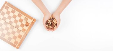 Beyaz arka plan üzerinde çocuk el satranç taşları ve satranç tahtası ile üstten görünüm