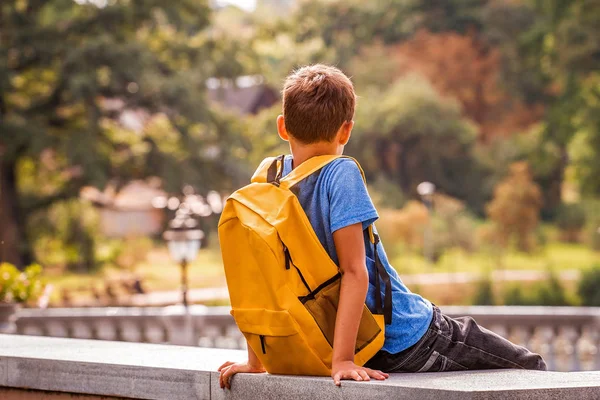 Tråkigt ensam pojke sitter i parken utomhus — Stockfoto