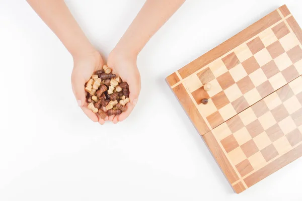 Vista superior de las manos de los niños con piezas de ajedrez y tablero de ajedrez sobre fondo blanco — Foto de Stock