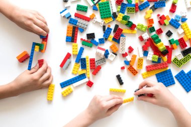 Vilnius, Litvanya - Nisan 2017. Çocukların elleri beyaz masada renkli lego bloklarıyla oynar..