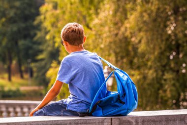 Çocuk okuldan sonra açık havada oturup sırt çantası ile