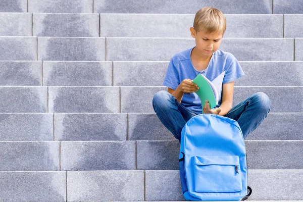 Pojke som läser boken sitter på trappan utomhus — Stockfoto