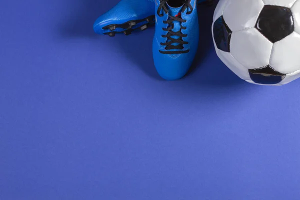 Bovenaanzicht van voetbal en paar voetbal voetbal sport schoenen op blauwe achtergrond — Stockfoto