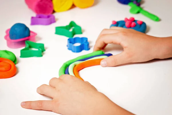 Child hands molding modeling clay or plasticine on white table — Stock Photo, Image