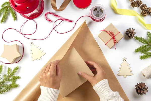 Kerst geschenkverpakking. Dames handen verpakking kerstcadeau vak in Kraft papier — Stockfoto