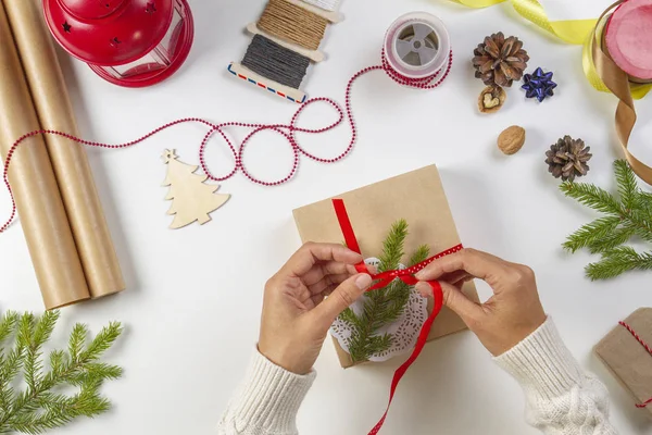 Empacotamento de presentes de Natal. Mãos de mulheres que embalam presentes de Natal na mesa branca — Fotografia de Stock