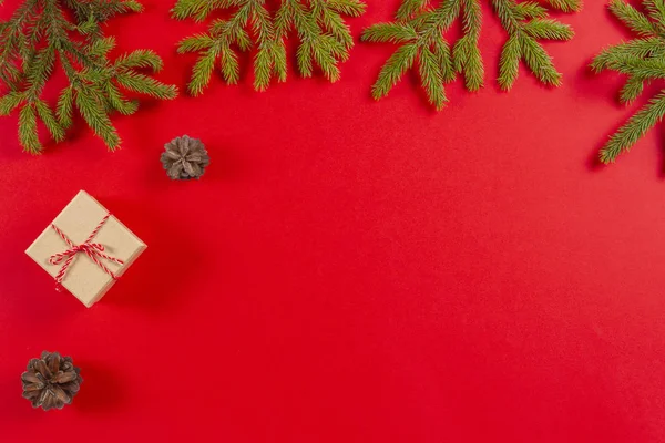 크리스마스 구성입니다. 전나무 나무 가지, 소나무 콘 및 빨간 배경에 현재 선물 상자 — 스톡 사진