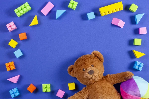 Baby hračky rámeček, děti s Medvídek, barevné koule, cihly a kostky na modrém pozadí. Pohled shora — Stock fotografie