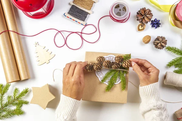 Christmas gift wrapping. Womans hands packing Christmas presents on white table