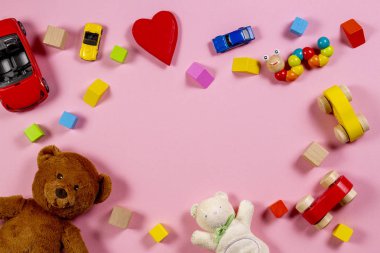 Bebek çocuklar oyuncak çerçeve oyuncak ayı, ahşap oyuncak araba, pembe bir arka plan üzerinde renkli tuğlalar ile. Üstten görünüm