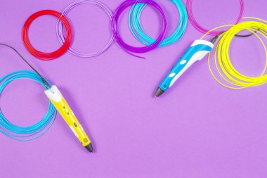 mor arka plan üzerinde renkli plastik filaman ile 3D kalemler