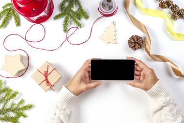 Planya, alışveriş online kavramı Noel. Cep telefonu ile kadın el, Noel hediyeleri, beyaz arka plan üzerinde süslemeleri