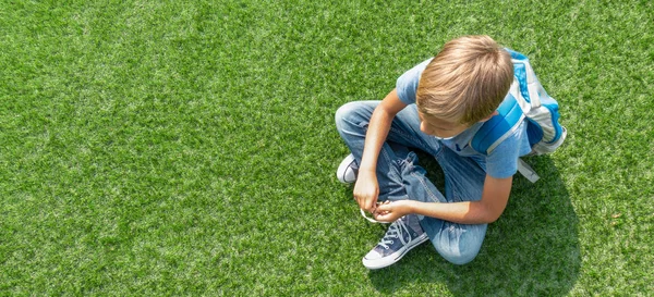 Infeliz triste chateado menino sentado sozinho na grama — Fotografia de Stock