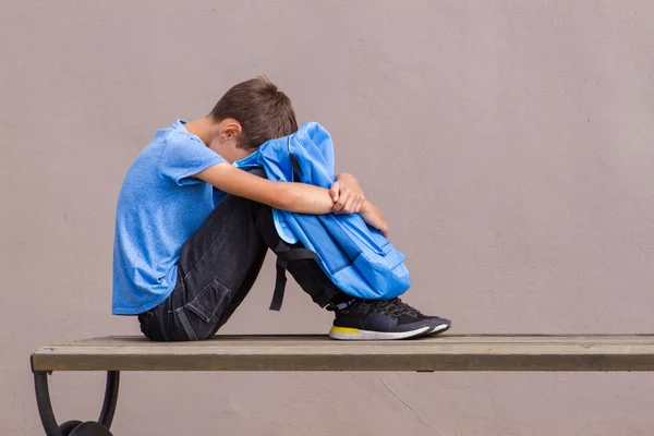 Niño triste y cansado sentado solo en el banco al aire libre . — Foto de Stock